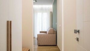A narrow hallway with a sofa and a radiator in the background. - Aurelius Design Loft 2 by Cornelia Subway (Roma)