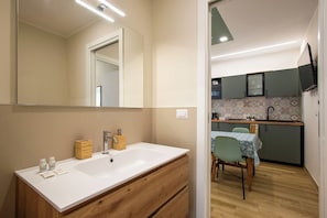 Un baño moderno con un espejo grande, lavamanos blanco, armarios de madera y tocador de madera.