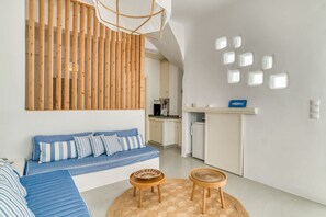 A modern living room with a blue sofa, wooden slats, and a kitchen in the background.