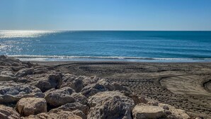 Una playa con grandes rocas al frente y un cielo azul despejado.