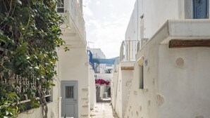 A narrow, stone-paved alleyway flanked by white buildings with balconies and a blue door. - Walkable distance from everything you need (Paros)
