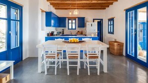 A modern kitchen with blue cabinets, a wooden ceiling, and a dining area with white chairs. - Alepou House - Gorgeous scenery (Aliki)
