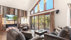 A spacious living room with a large TV, comfortable seating, and a balcony with a scenic view. - 34 Acre Escape~Games~Hiking~Pool Table~Bicycles (Black Hawk)