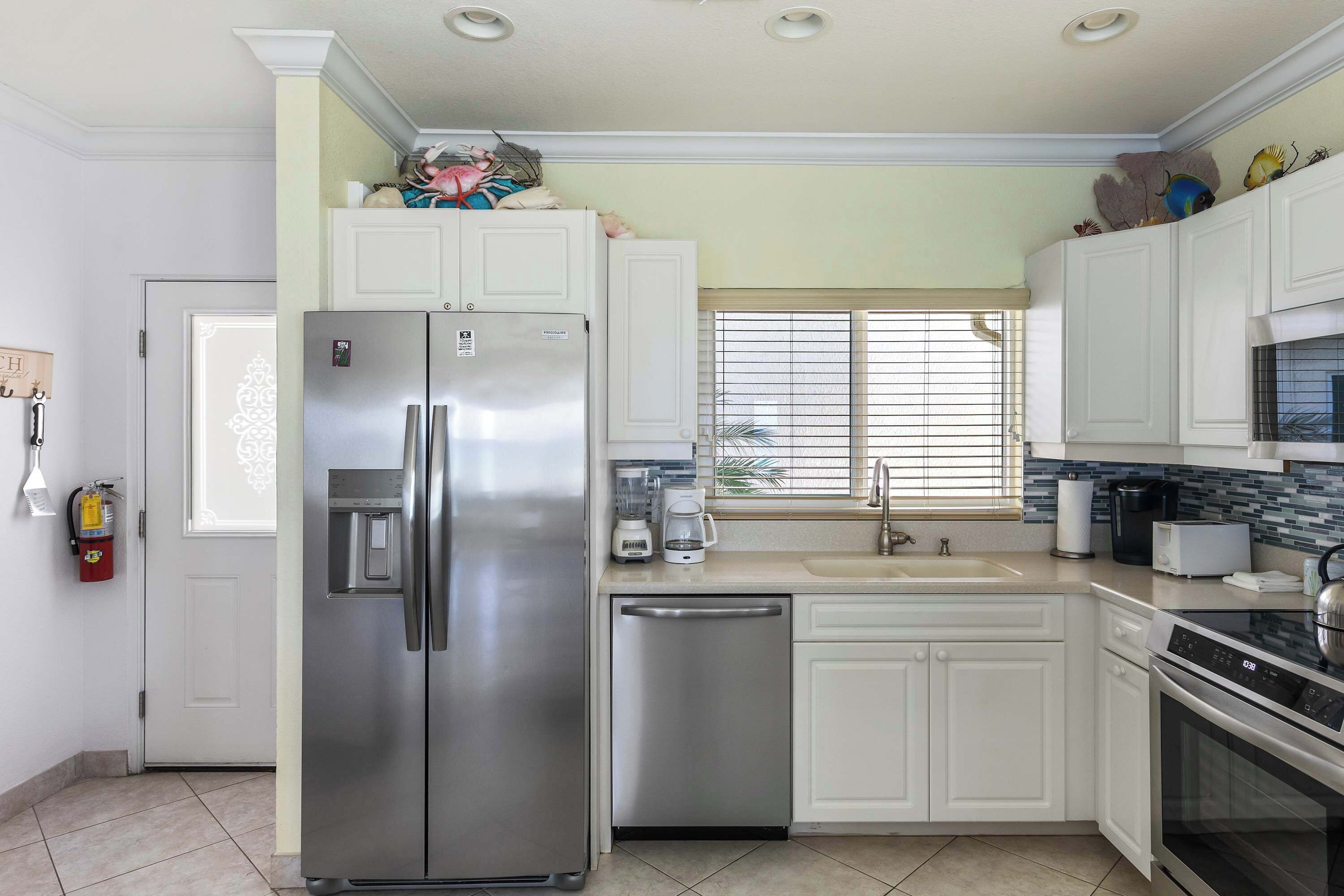 A modern kitchen with white cabinets, stainless steel appliances, and a tiled backsplash.