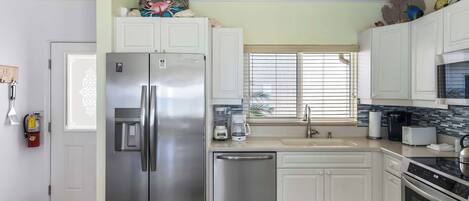 A modern kitchen with white cabinets, stainless steel appliances, and a tiled backsplash.