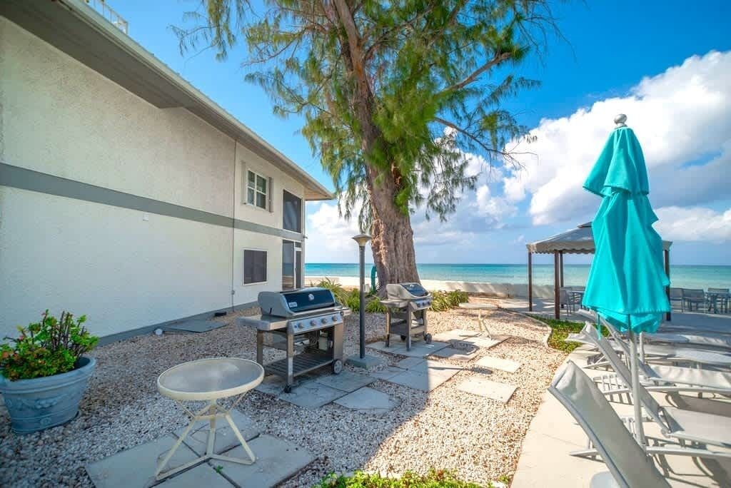 A patio with a grill, lounge chairs, and a view of the ocean.