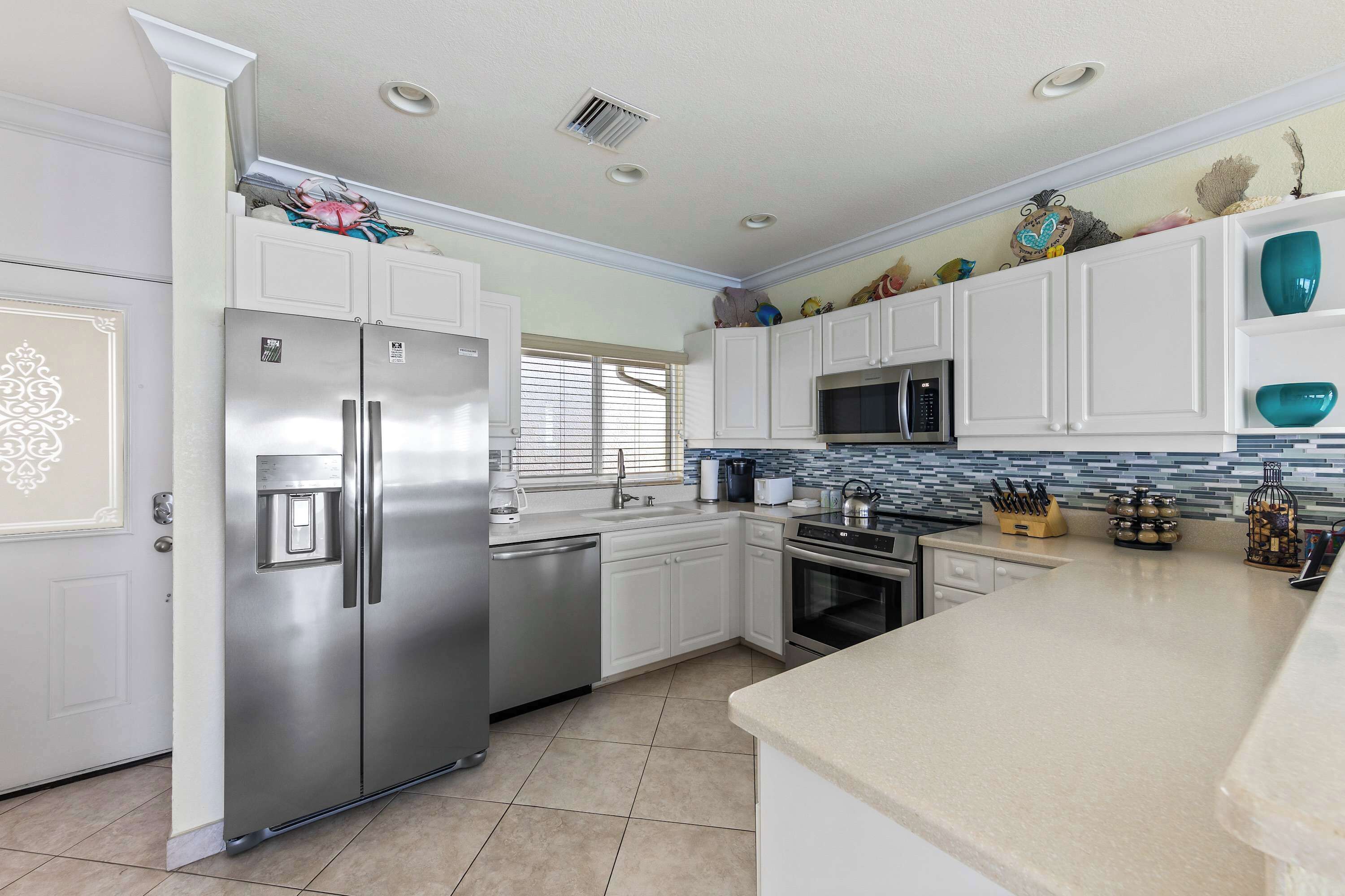 A modern kitchen with white cabinetry, stainless steel appliances, and a tiled backsplash.