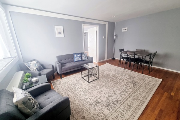The living room comes furnished with essential pieces, including a comfortable sofa, a coffee table, TV stand, and dining table, providing immediate comfort upon move-in.