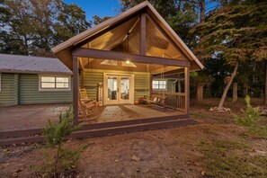 Una cabaña de troncos con un porche, una terraza de madera y un letrero acogedor.