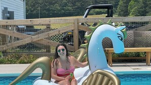 A person in a pink swimsuit sitting on a gold and white inflatable horse in a swimming pool. - Farm Experience in a Beautiful Log Cabin (LaFayette)