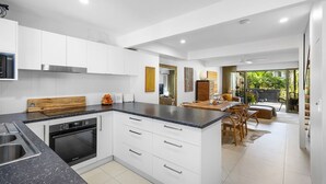 Une cuisine moderne avec des meubles blancs, un plan de travail en granit et un four encastré.
