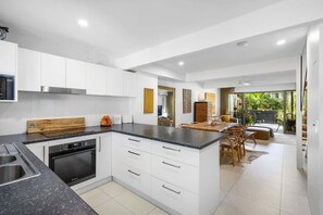 Una cucina moderna con mobili bianchi, un piano di lavoro nero e un forno integrato.