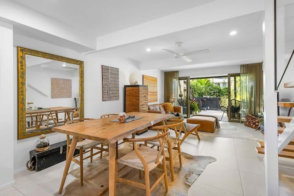 A spacious dining area with a wooden table and chairs, a large mirror, and a view of the outdoor patio.