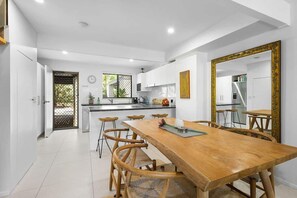 Una cucina moderna con mobili bianchi, un tavolo da pranzo in legno e un grande specchio con cornice decorativa.