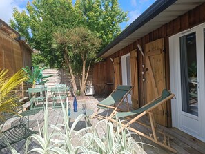 A wooden deck with outdoor furniture, a tree, and a sliding glass door. - La BISCABANE quiet bicycle path near lakes shopping center Classified **** (Biscarrosse)