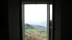 Une vue à travers une fenêtre, offrant une perspective dégagée sur un paysage comprenant des champs et des collines lointaines.