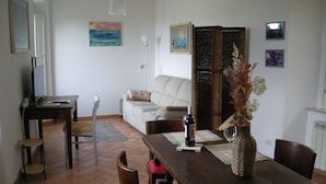 Un salon comprenant un canapé, une table à manger avec des chaises, un téléviseur et un vase décoratif.