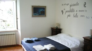 Une chambre à coucher comprenant un lit, une table de chevet, un radiateur, une fenêtre et un mur orné d’une citation inspirante.