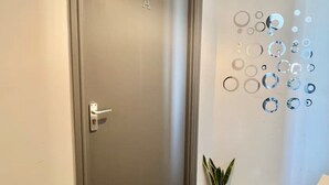 A door with a metal handle, a welcome mat, and a wall with circular mirrors. - Studio in Southwark (Londres)