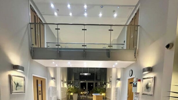 A spacious lobby with a high ceiling, a central reception desk, and a staircase leading to an upper level. - Studio in Southwark (Londres)