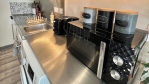A modern kitchen with stainless steel appliances, a built-in oven, and a coffee machine. - Studio in Southwark (Londres)