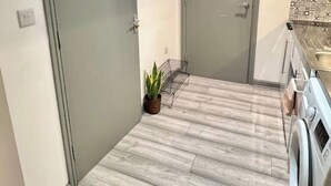 A modern kitchen with a washing machine, a drying rack, and a potted plant. - Studio in Southwark (Londres)