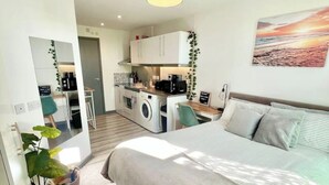 A compact bedroom with a bed, a small kitchenette, a washing machine, and a mirror. - Studio in Southwark (Londres)