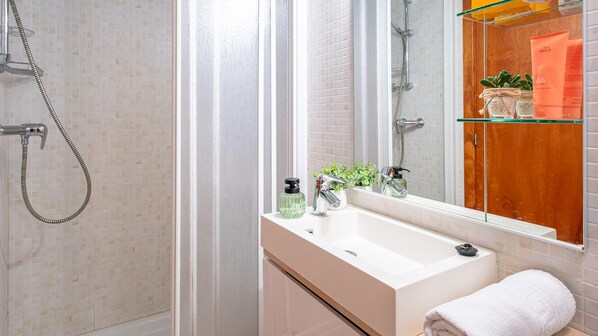 Un baño moderno con ducha, lavamanos y espejo.