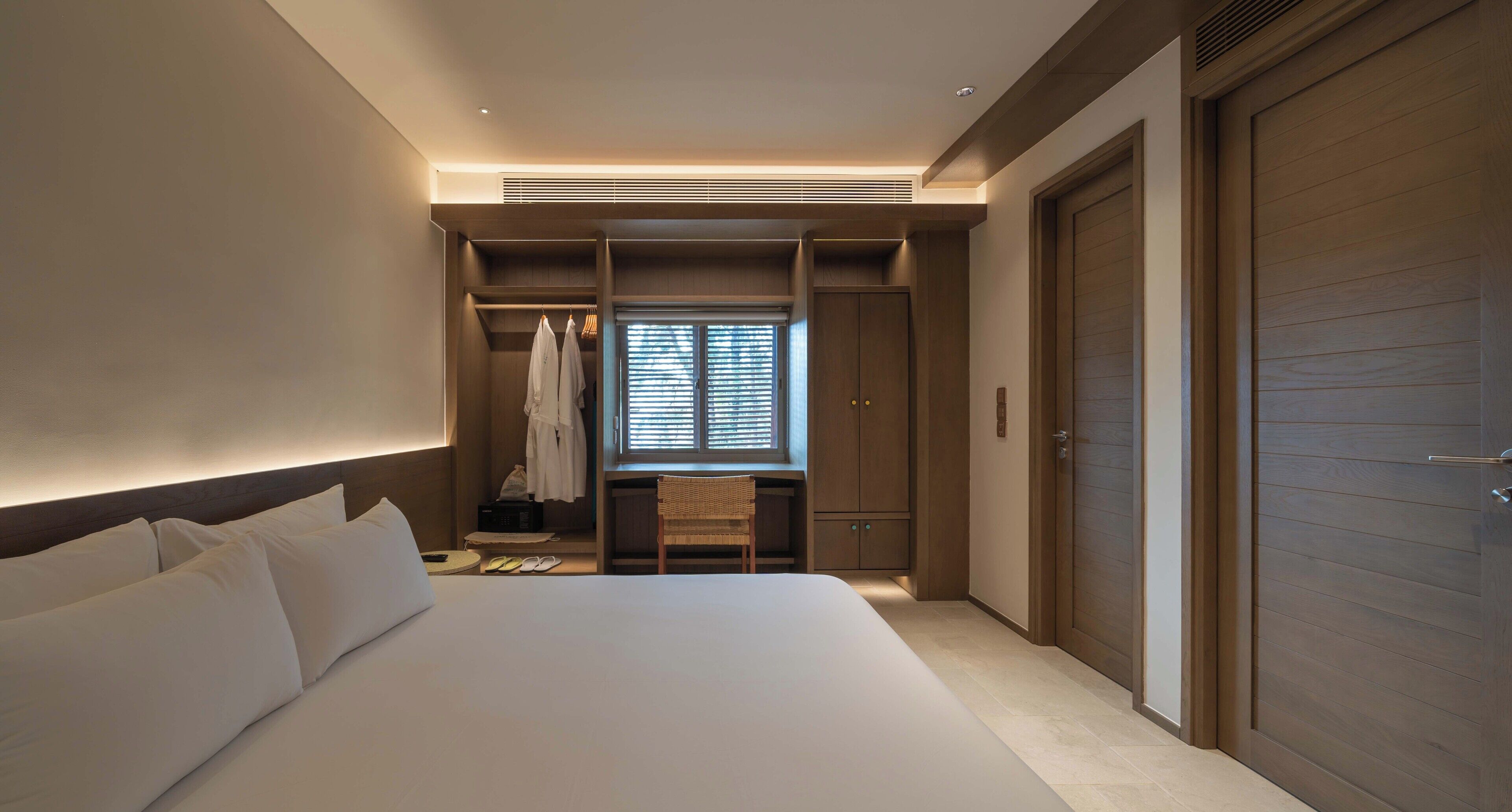 A hotel room with a large bed, a walk-in closet, and a sliding door.