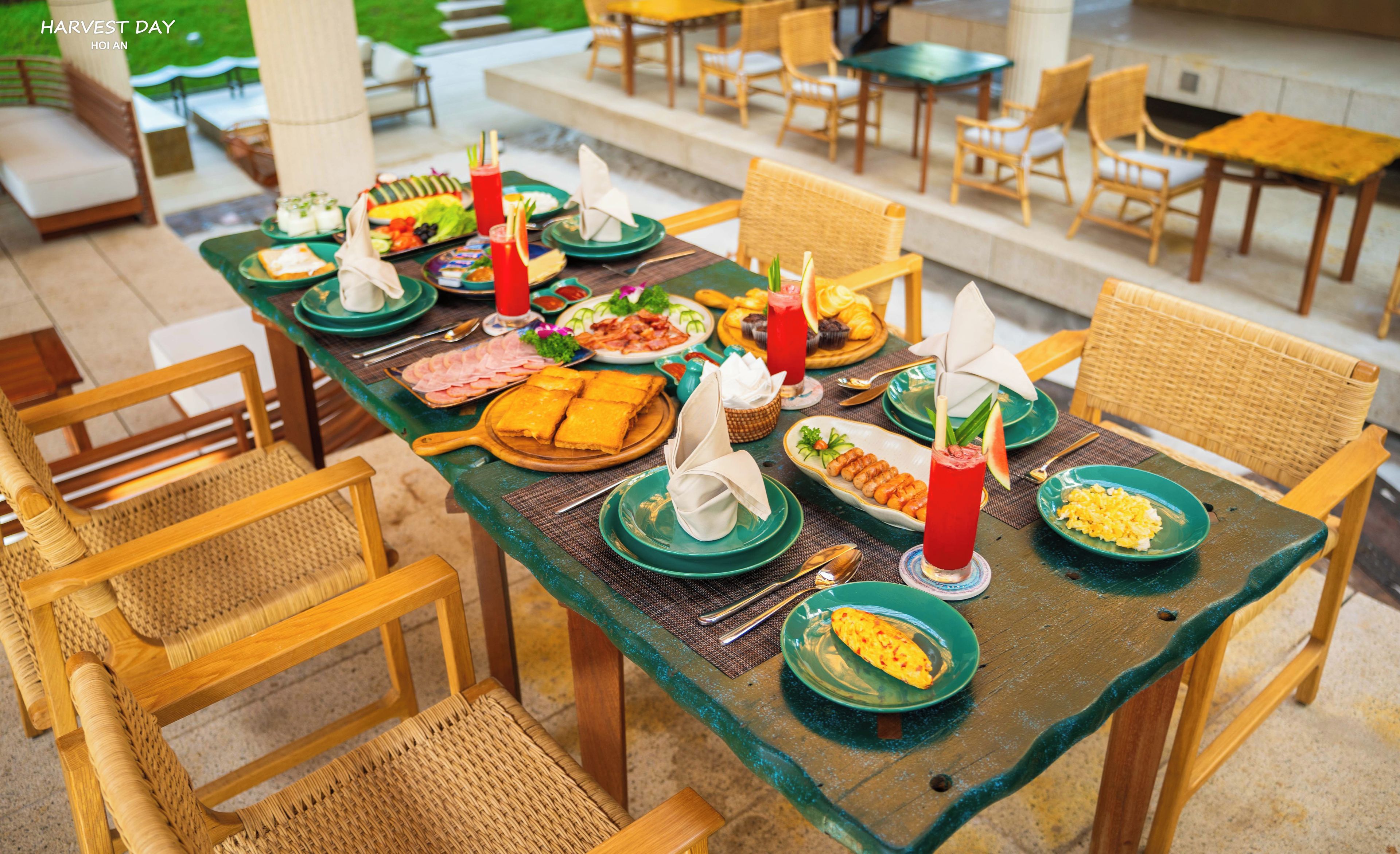 A dining table set with various dishes, surrounded by wicker chairs in an outdoor dining area.