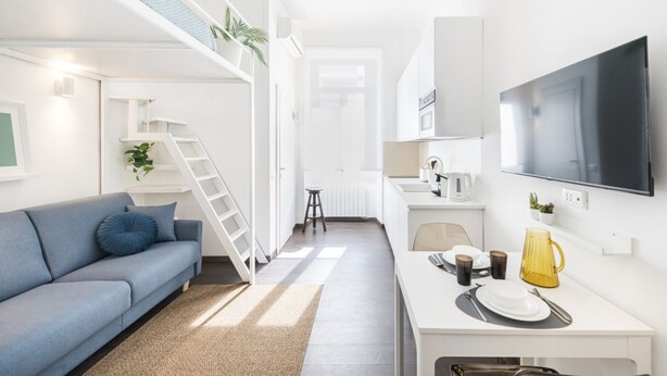 A modern, compact living space with a sofa, a dining area, a kitchen, and a TV.