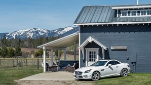 A white car parked in front of a building with a covered patio and a mountain view in the background.