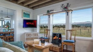 A cozy living room with a fireplace, a TV mounted on the wall, and a scenic view through large windows.