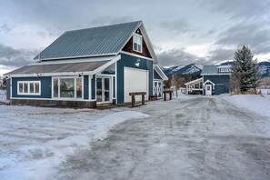 A two-story building with a garage, a covered porch, and a mountain backdrop.