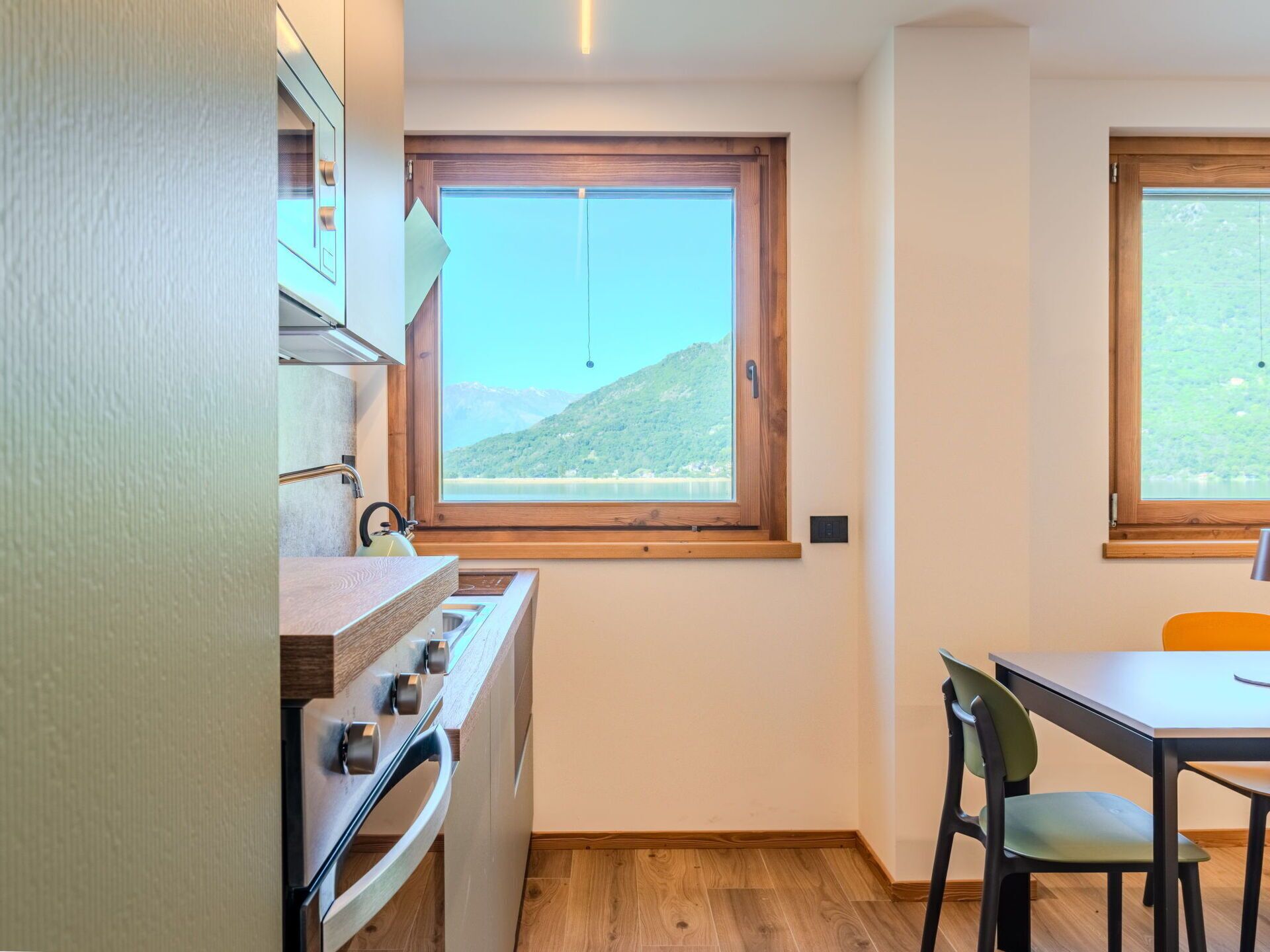 Une cuisine compacte dotée d’une fenêtre donnant sur les montagnes, d’une table à manger avec une chaise et d’un four encastré.