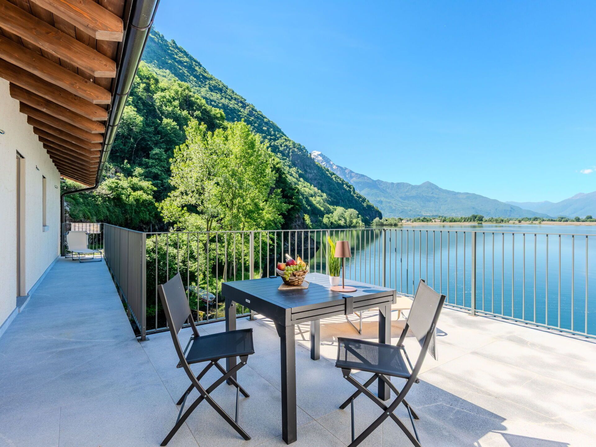 Ein Balkon mit Tisch und Stühlen mit Blick auf einen See und Berge.