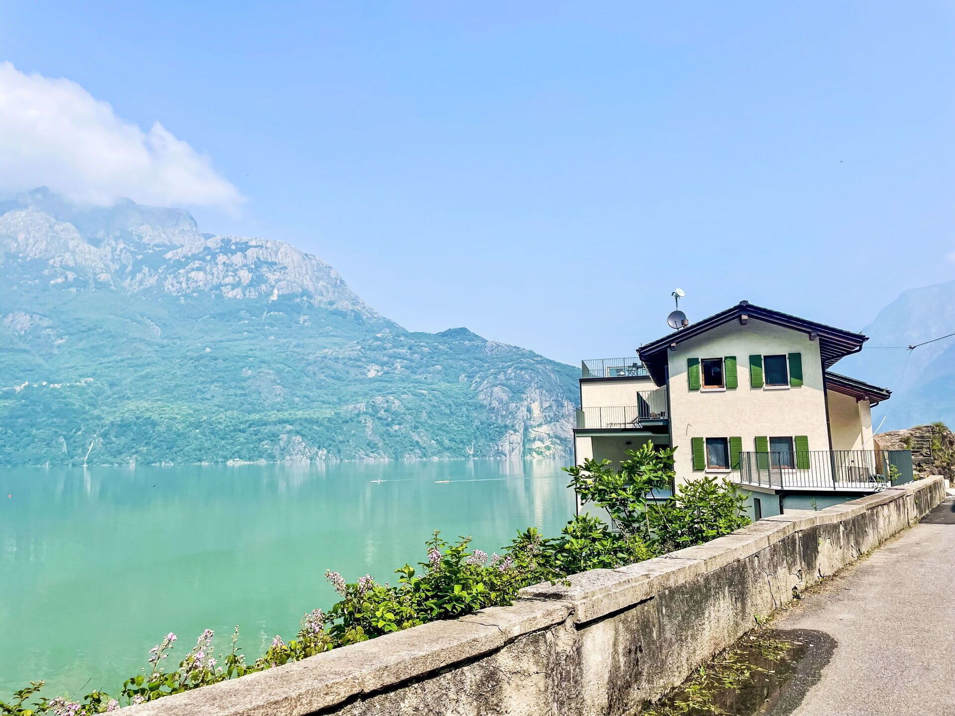 Un edifici de dues plantes amb un balcó, amb vista a un llac tranquil i muntanyes.