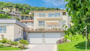Une maison moderne à deux étages, dotée d’un garage, d’un balcon et d’une allée pavée.