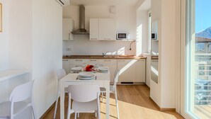 Une cuisine moderne avec des meubles blancs, un plan de travail en bois et un coin repas avec des chaises blanches.