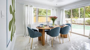 A dining area with a round table, six chairs, and a ceiling fan.