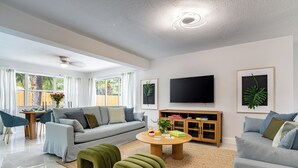 A modern living room with a grey sofa, a round coffee table, and green ottomans.