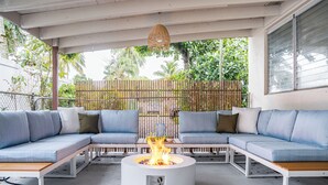A covered outdoor seating area with a central fire pit surrounded by blue sofas and cushions. - Your World Cup HQ: Near Miami Stadium - Pool (Fort Lauderdale)