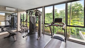 Ein modernes Fitnessstudio mit vielfältigen Trainingsgeräten, großen Fenstern mit Blick ins Grüne und einer aufgeräumten, geräumigen Gestaltung.