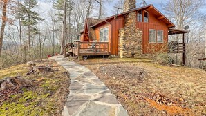 A rustic cabin with a stone chimney, wooden deck, and a stone pathway leading to the entrance. - Chaco`s Chalet Cabin in the Smokies (Franklin)