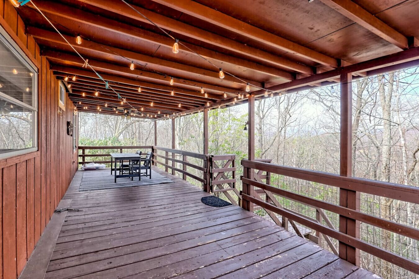 A wooden deck with a table and chairs, surrounded by a wooden railing.