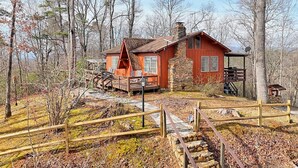 A rustic cabin with a stone chimney, wooden deck, and a small porch. - Chaco`s Chalet Cabin in the Smokies (Franklin)