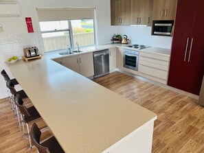 A modern kitchen with a large island, stainless steel appliances, and wooden flooring.