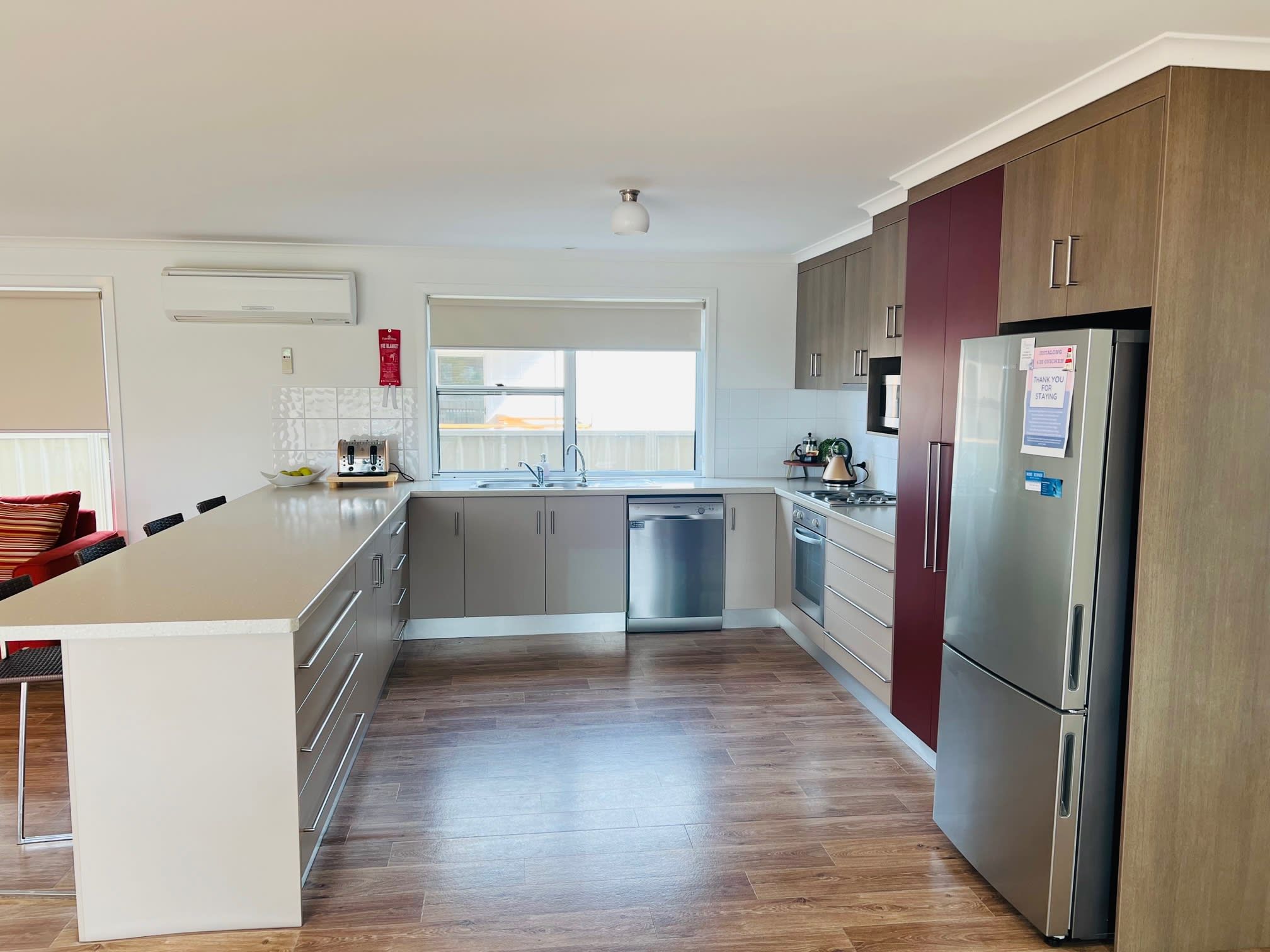 A modern kitchen with a central island, stainless steel appliances, and a view to the outside.