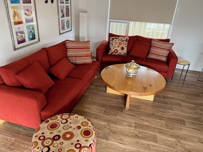 A living room with two red sofas, a wooden coffee table, and a patterned ottoman.
