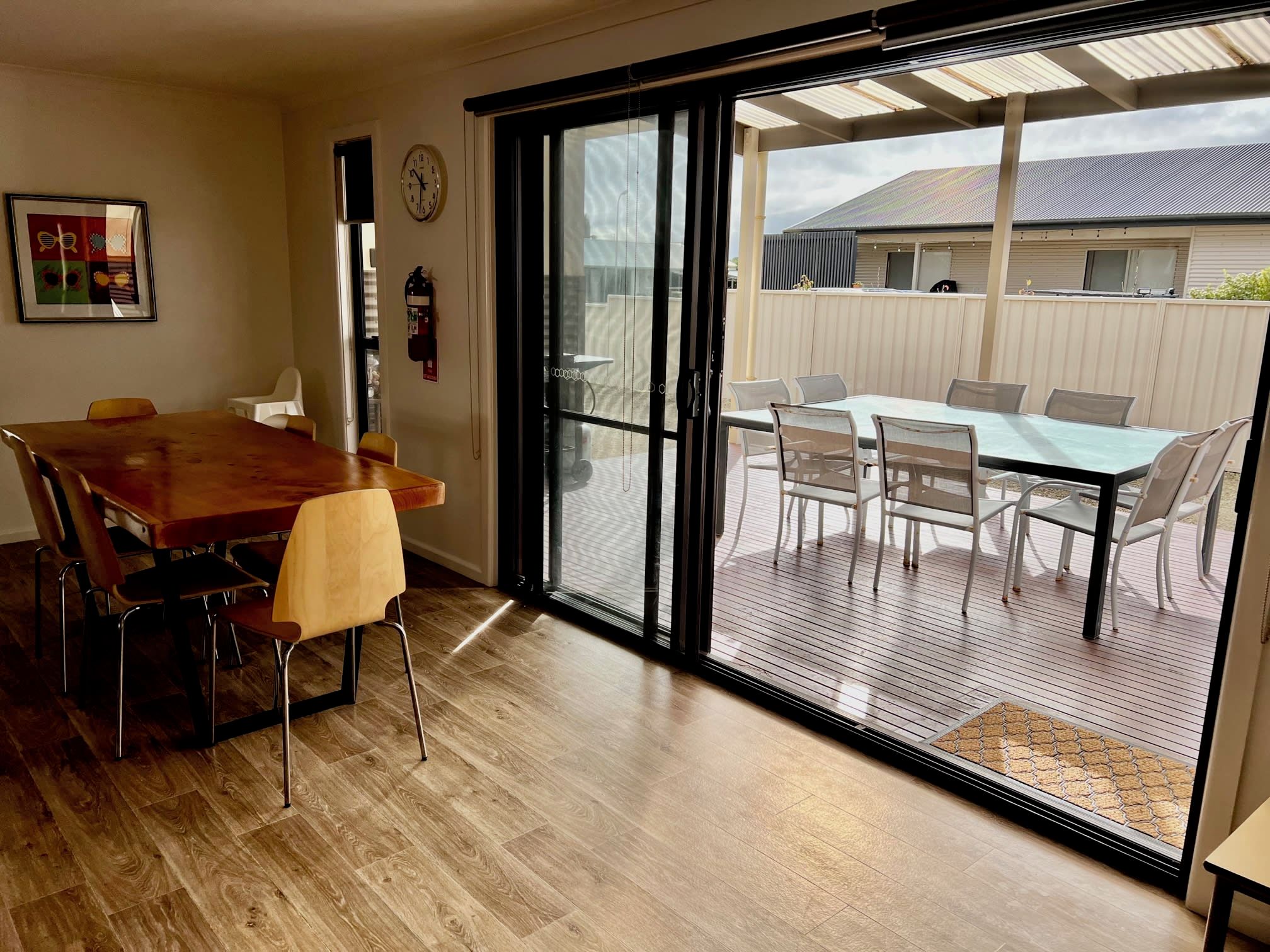 A dining area with a wooden table and chairs, a sliding glass door leading to an outdoor patio with a table and chairs.